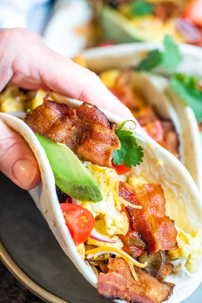 Hand holding breakfast taco close to the camera lens.