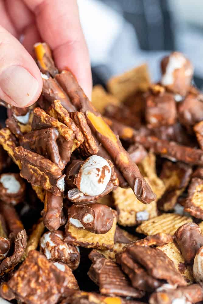 Hand picking up s'mores trail mix out of bowl.