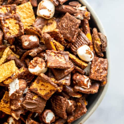 Overhead shot of snack mix in a bowl on a white counter.