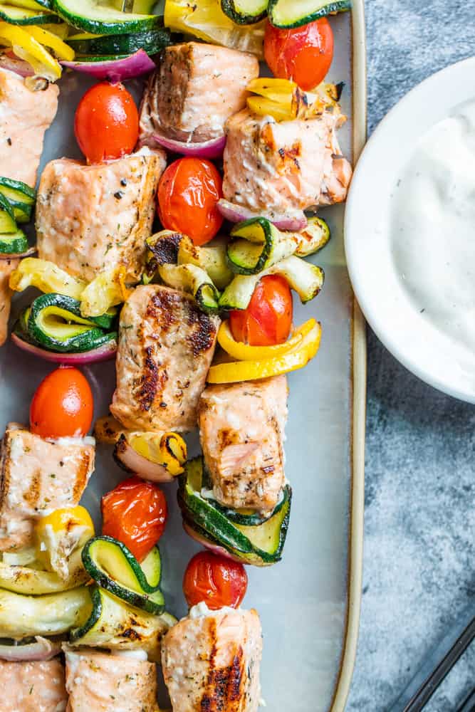 Overhead shot of grilled salmon on a gray plate on a blue counter.