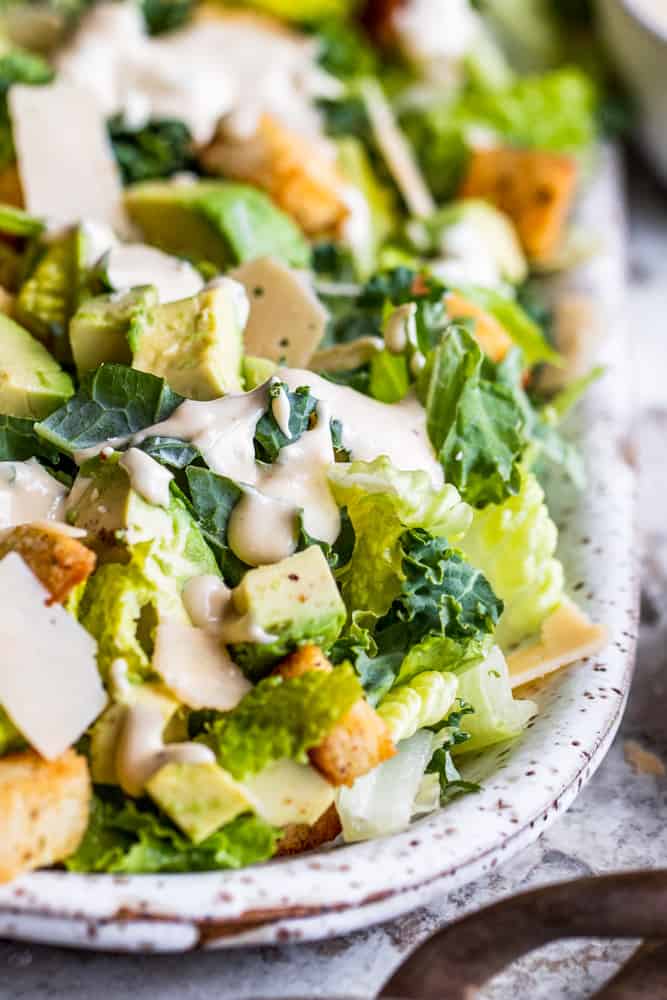 Caesar salad on a white platter on a white counter.