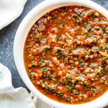 Overhead shot of salsa in a white bowl on a blue counter.