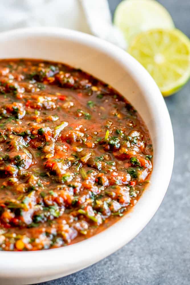 Close up shot of salsa in a white bowl on a blue counter.