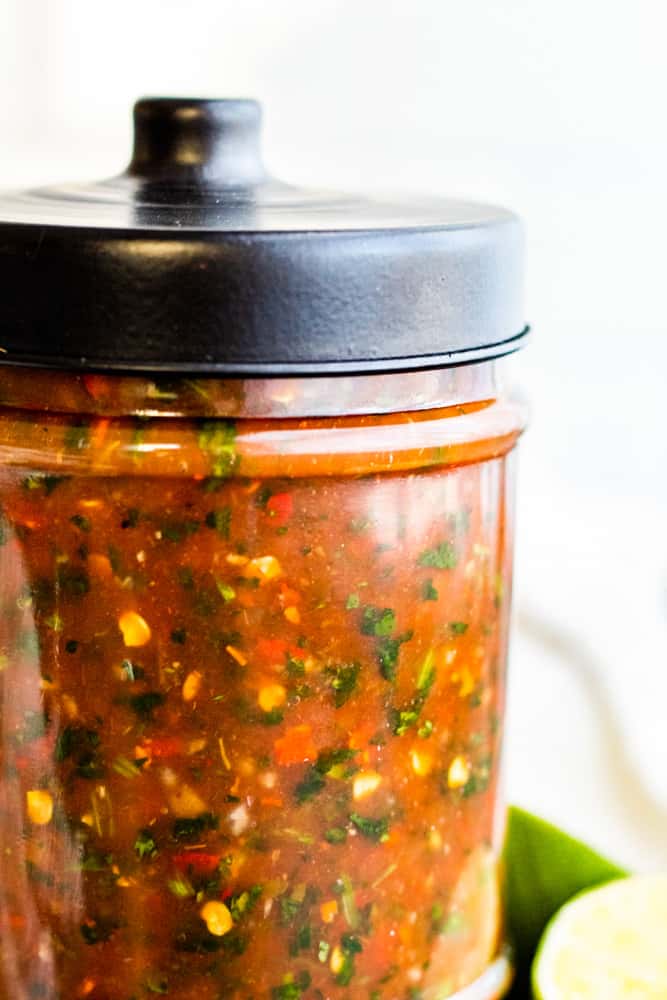 Mason jar with black lid filled with restaurant style salsa.