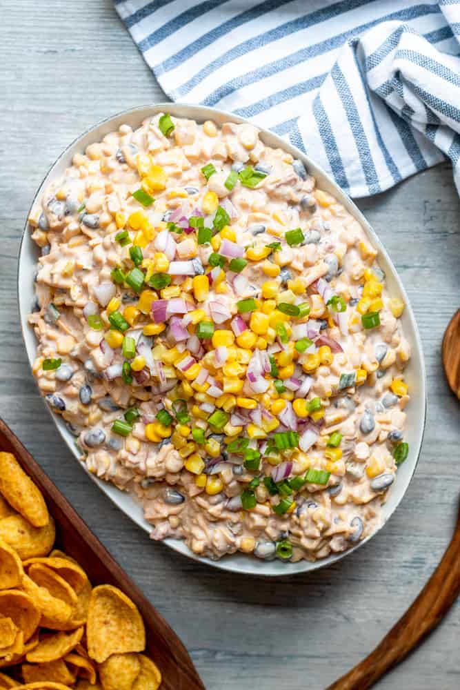 Overhead shot of dip in a white bowl on a white counter with chips on the side.