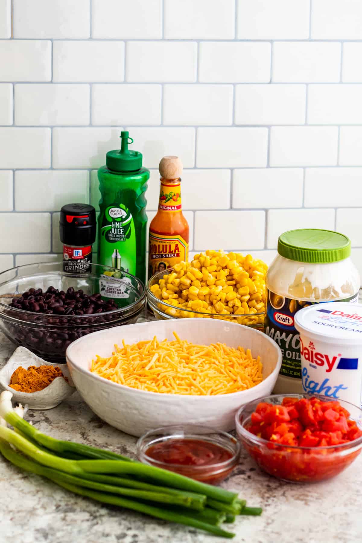 Ingredients for dip in bowls and containers laid out on white counter.