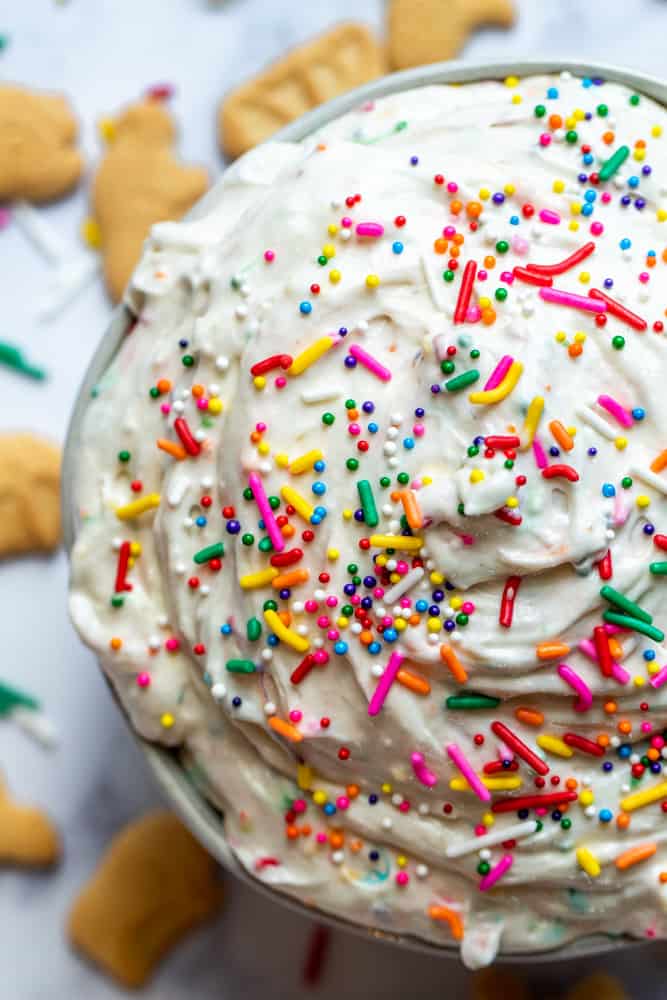 Overhead close up shot of funfetti dip in a white bowl on a white counter with animal crackers.