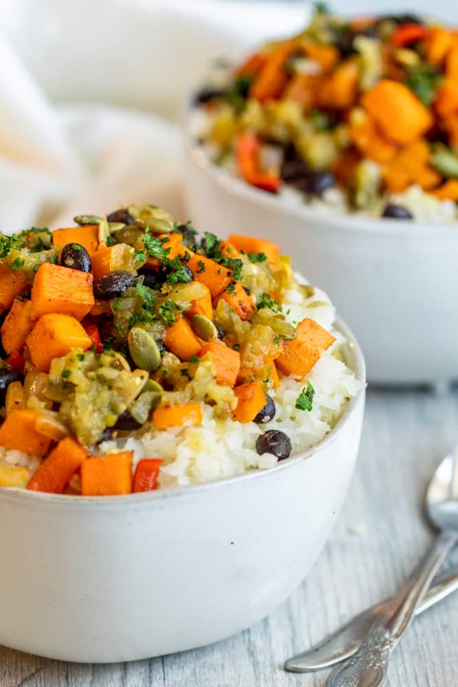 Two white bowl with filling in them with silver spoons.