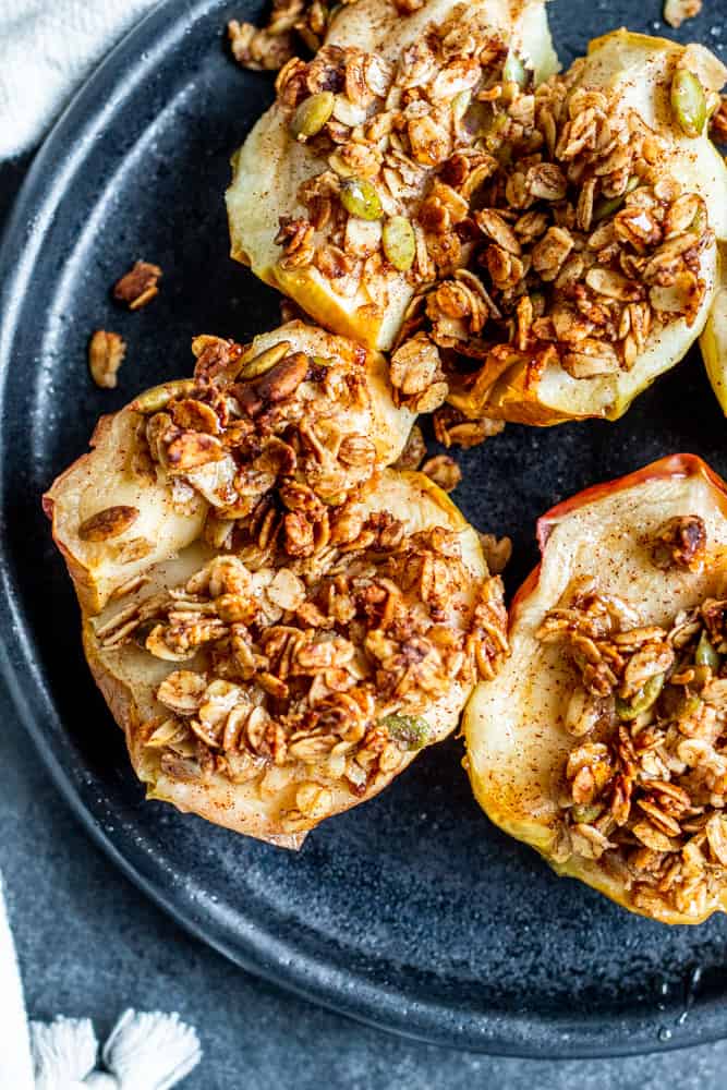 Overhead shot of baked apples on a black plate.