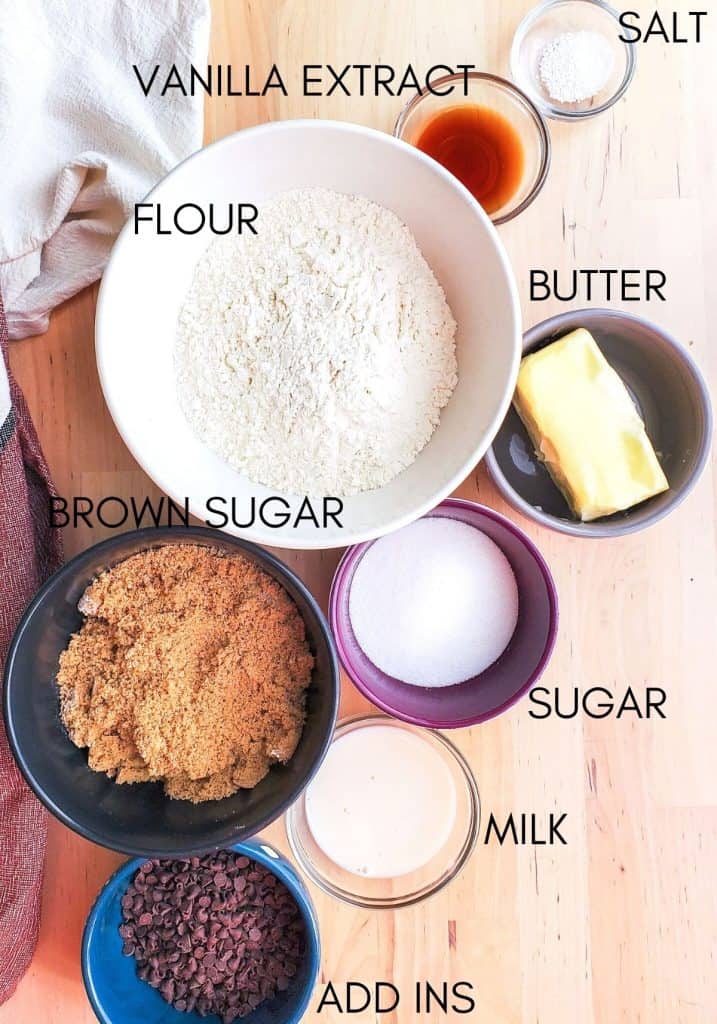 Overhead shot of cookie dough ingredients in small bowls with names in black text.