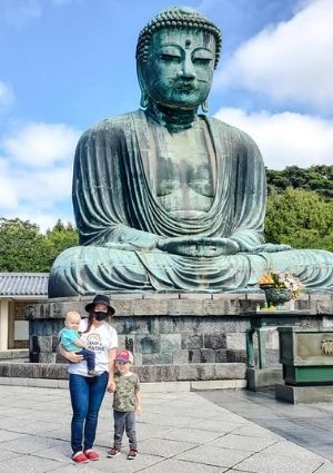 Mom with two son in front of buddha statue.