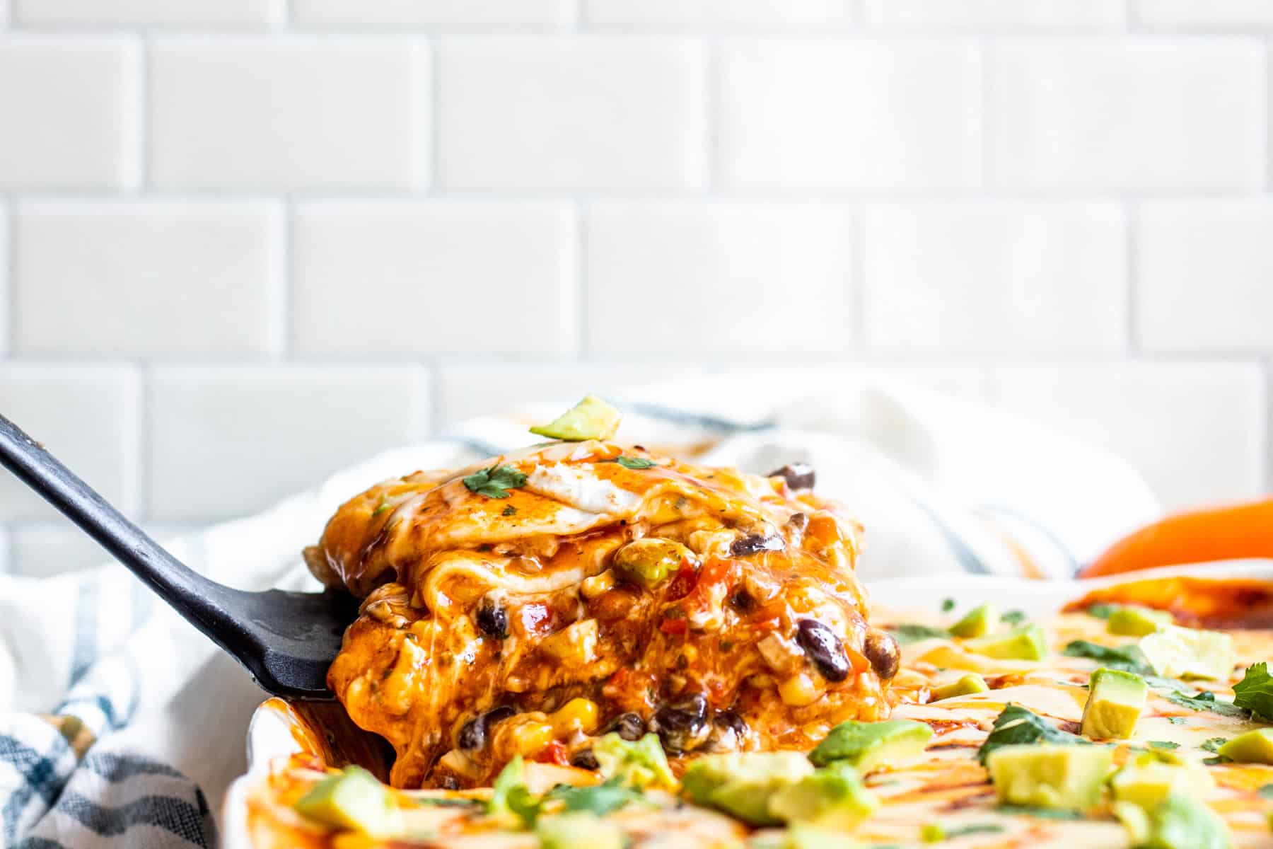 Spatula scooping out taco casserole of baking dish.