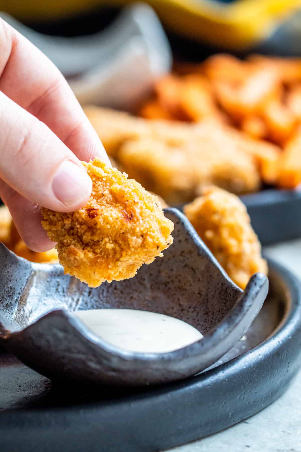 Popcorn chicken being dipped in ranch.