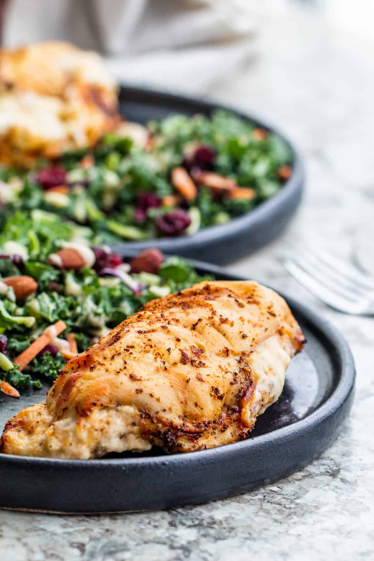 Cheese stuffed chicken on a black plate with side salad on a white counter.