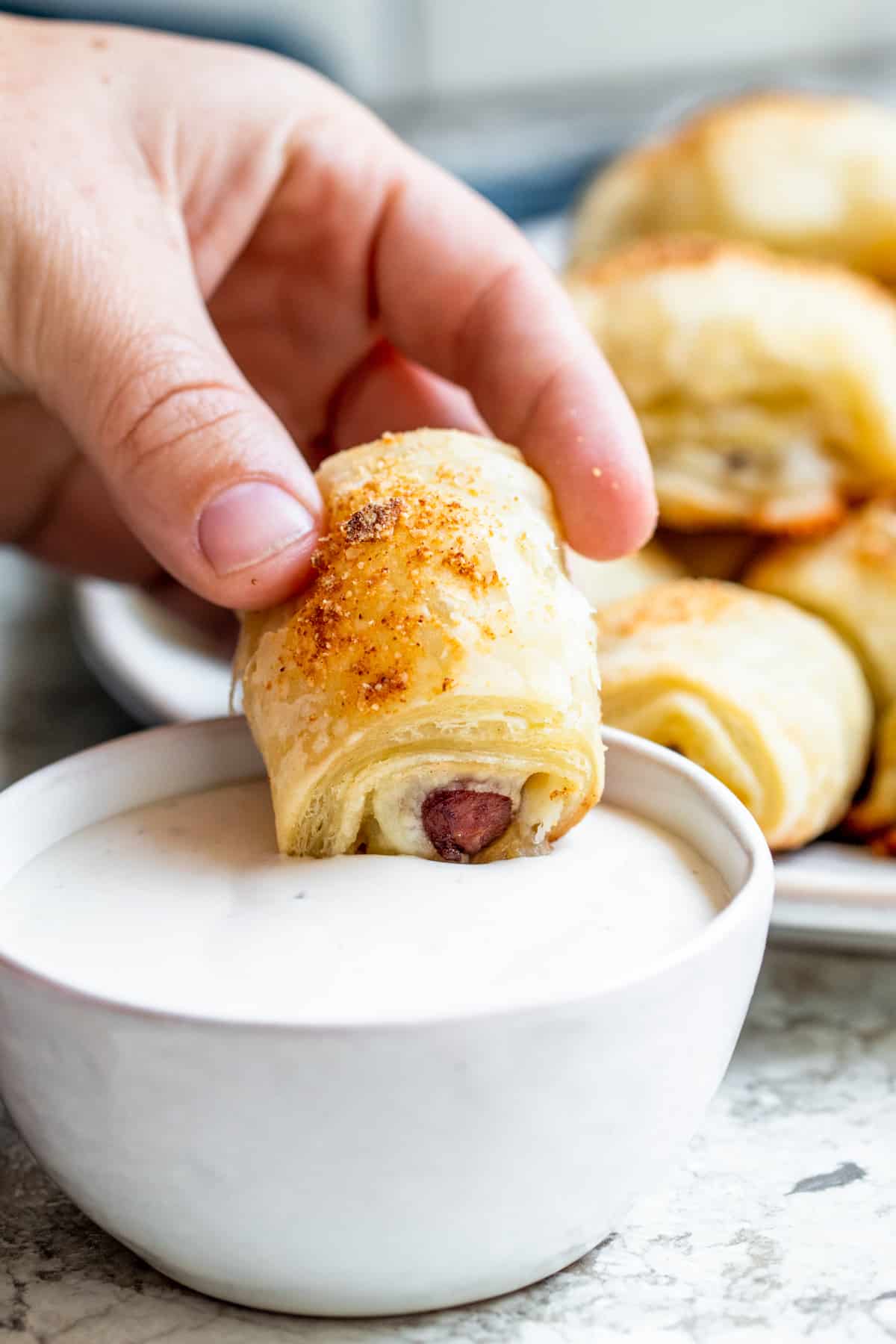 Hand dipping mini crescent dog into ranch dressing.