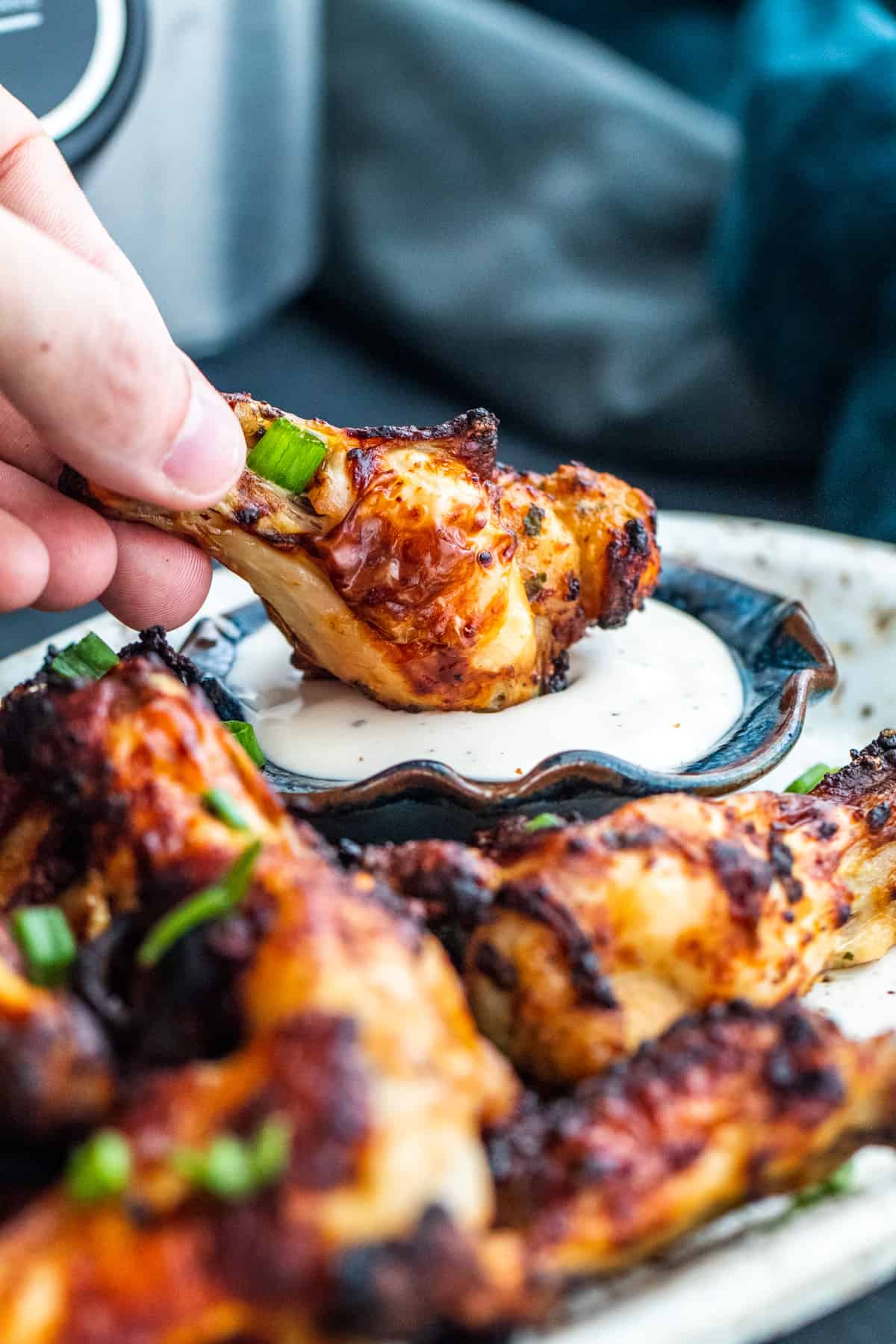 Hand dipping wing into small bowl of ranch.