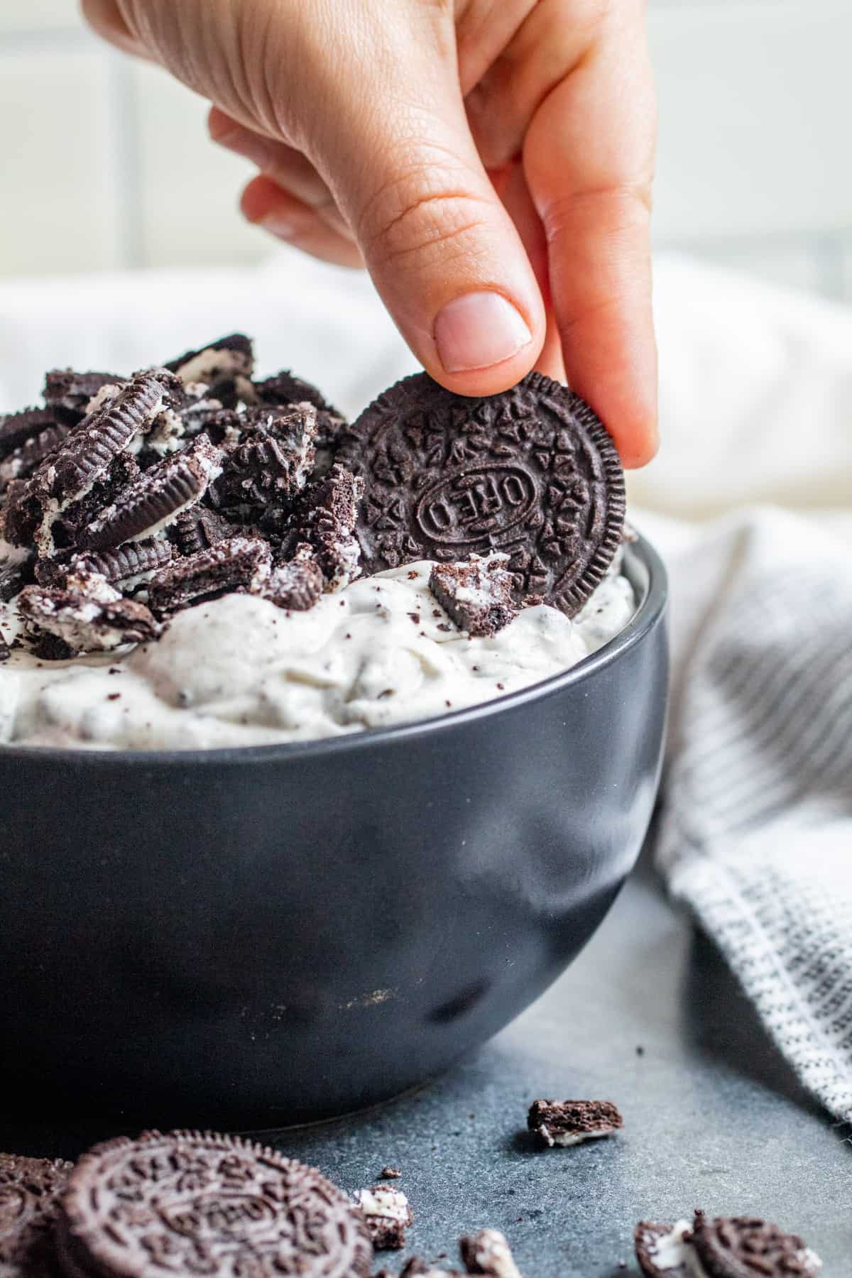 Hand dipping oreo cookie into dip.