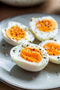 Close up of sliced hard boiled eggs on gray plate.