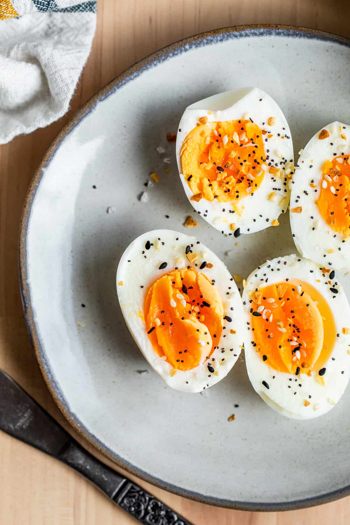 Overhead shot of peeled and sliced boiled eggs on gray plate.